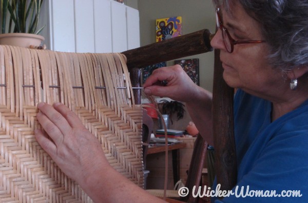 Cathryn Peters using an American caning needle on a wide binding cane twill seat.