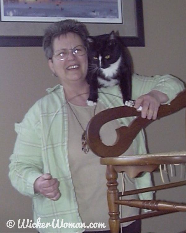 Cathryn and her caning shop cat, Don Gato, perched on her shoulder.