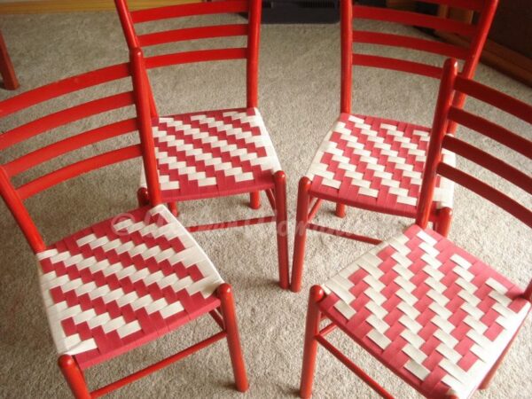 Four red chairs with Shaker tape seats in a red and white twill pattern.
