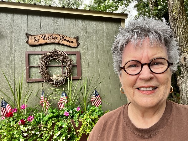 The Wicker Woman® Cathryn Peters standing in front of her wicker weaving studio. 