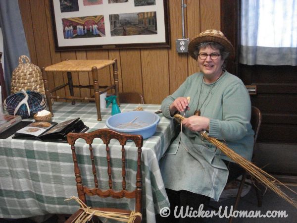 Cathryn Peters demonstrating weaving a coiled straw bee skep.