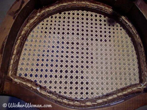 Underside of horseshoe shaped chair frame, showing the "no-knot" chair caning technique.