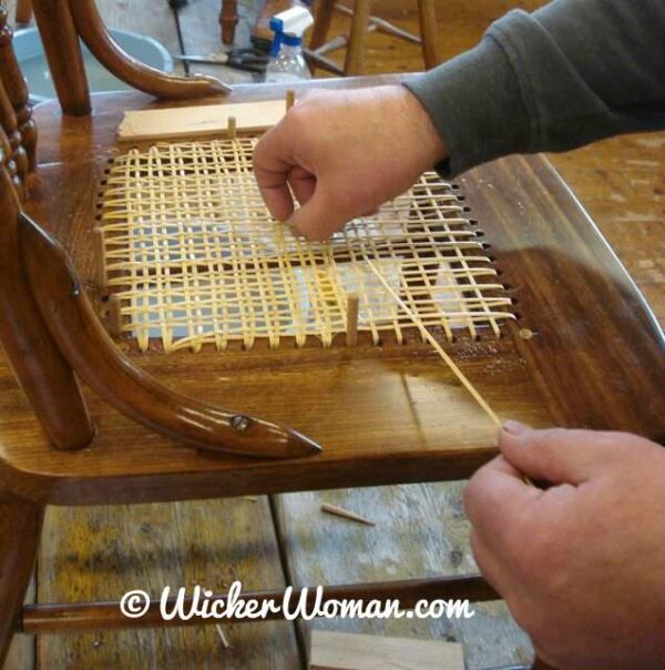 Strand chair cane weaving-pulling through the cane in the right direction.